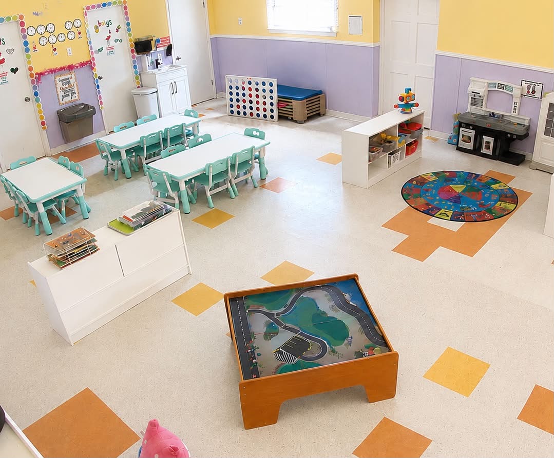 Preschool classroom with teal activity tables, play kitchen and a train table