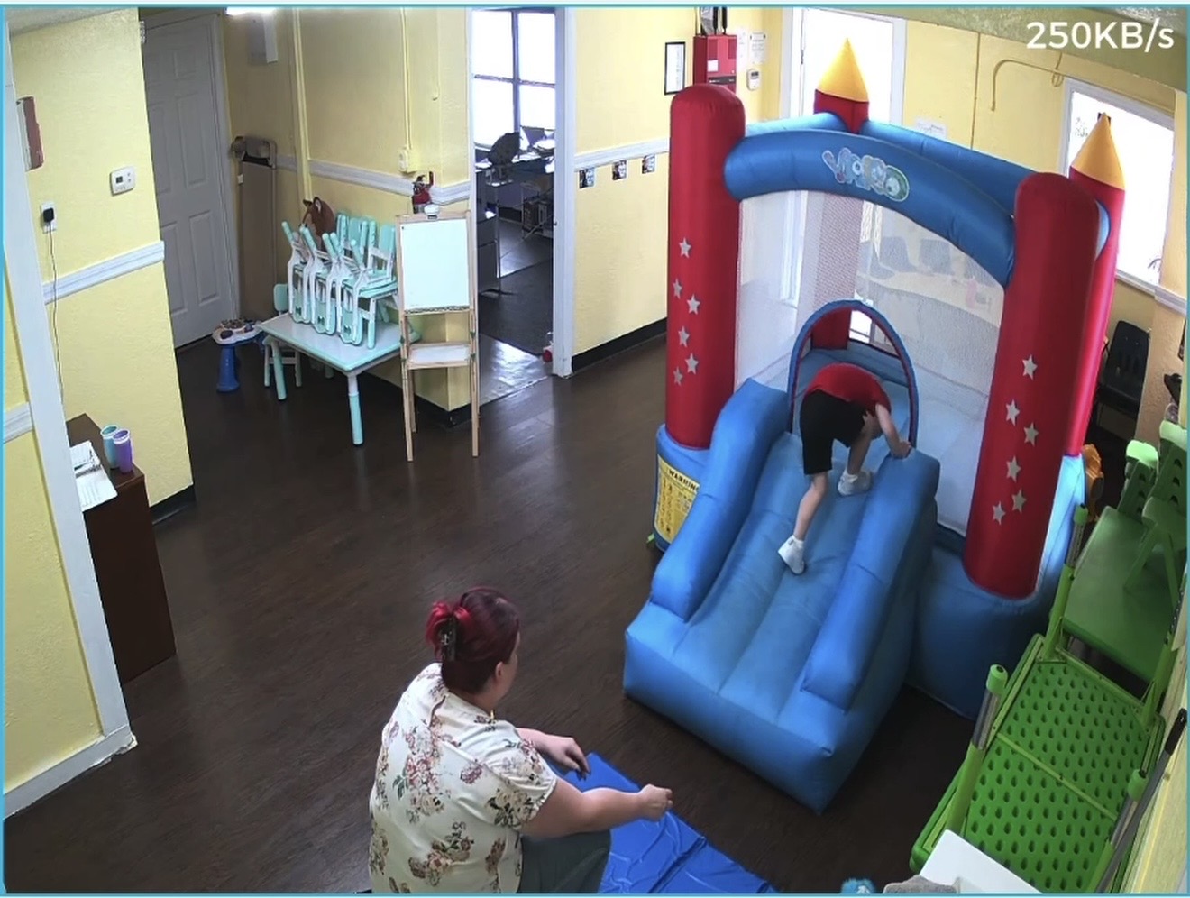 Indoor bounce house play area with a teacher nearby