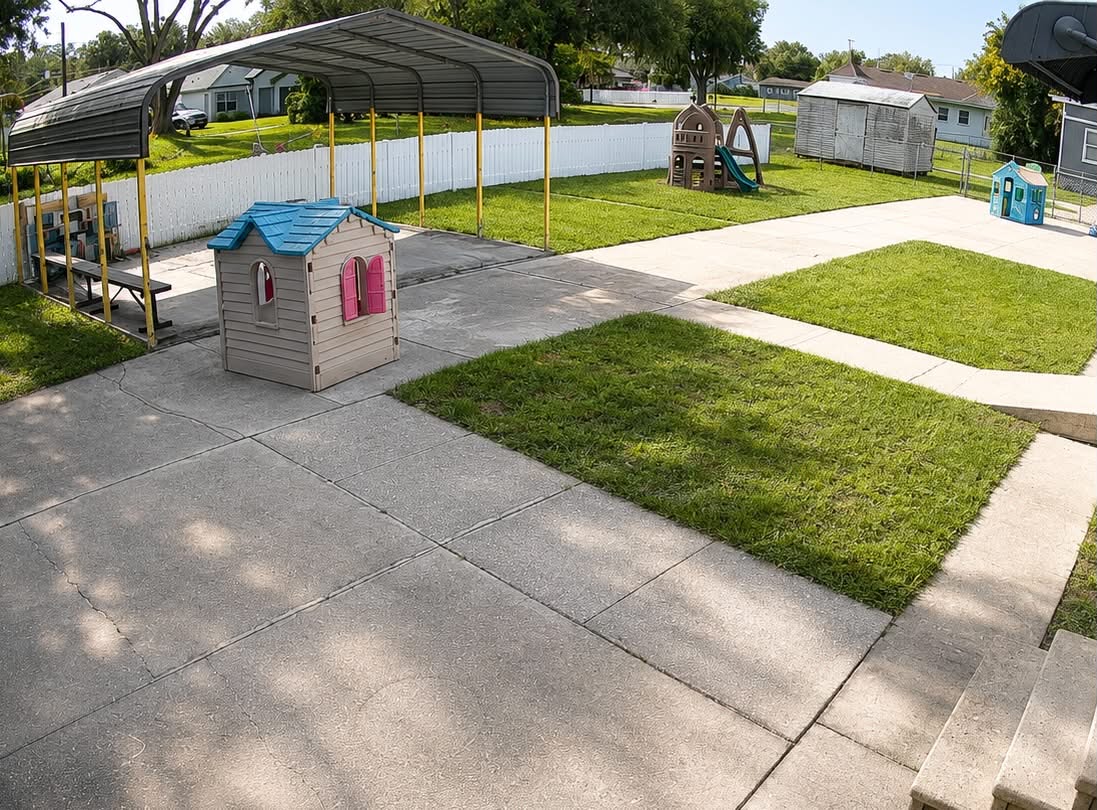 Fenced outdoor playground with playhouses, slide and shaded picnic area