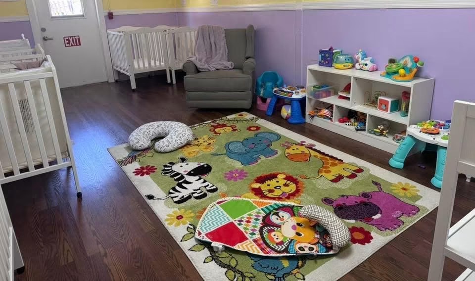 Infant room with cribs, soft play mats and toy shelves